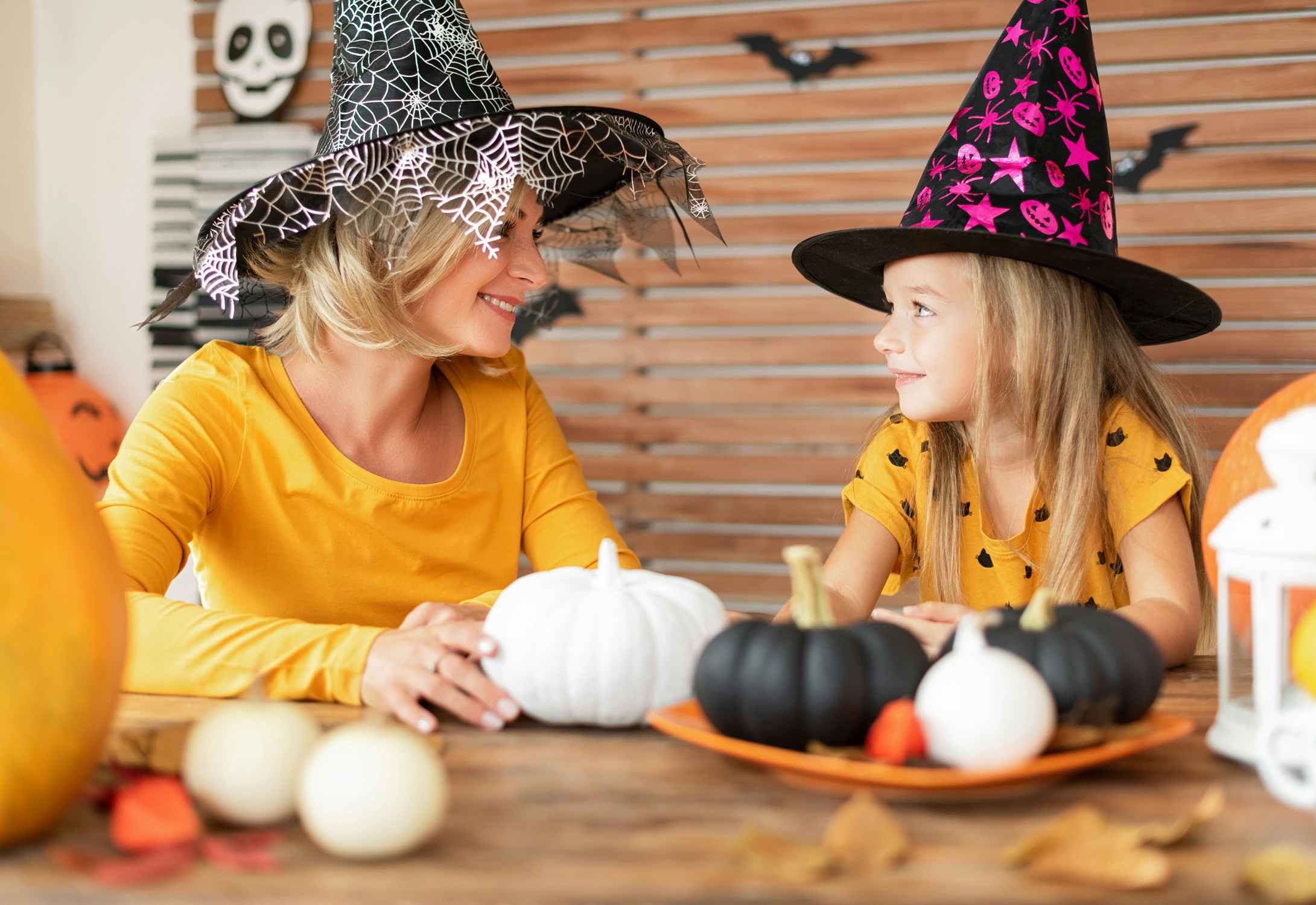 woman and daughter dressed in Halloween witch hats with pumpkins
