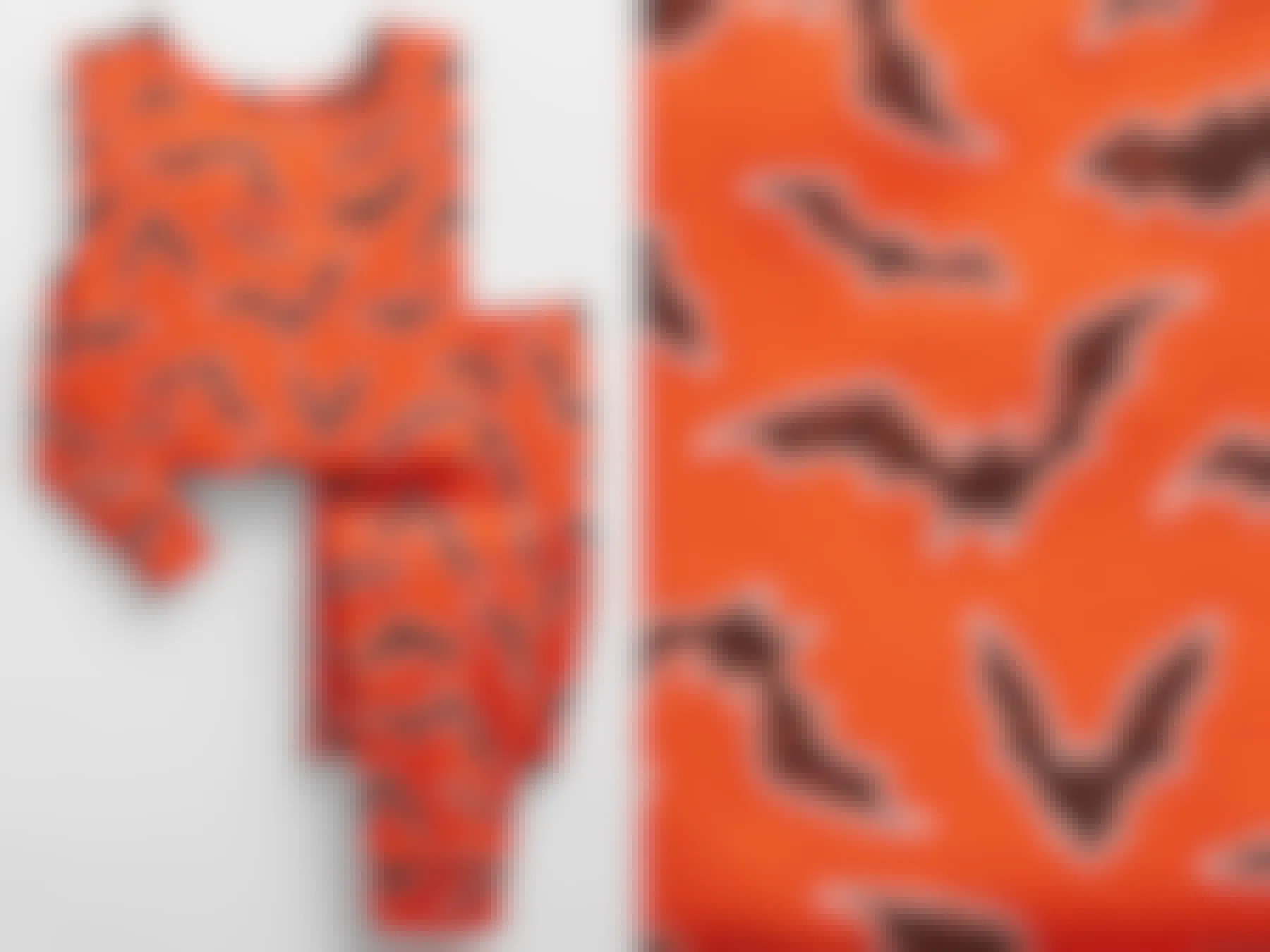 A pair of orange halloween pajamas with black bats printed all over them.