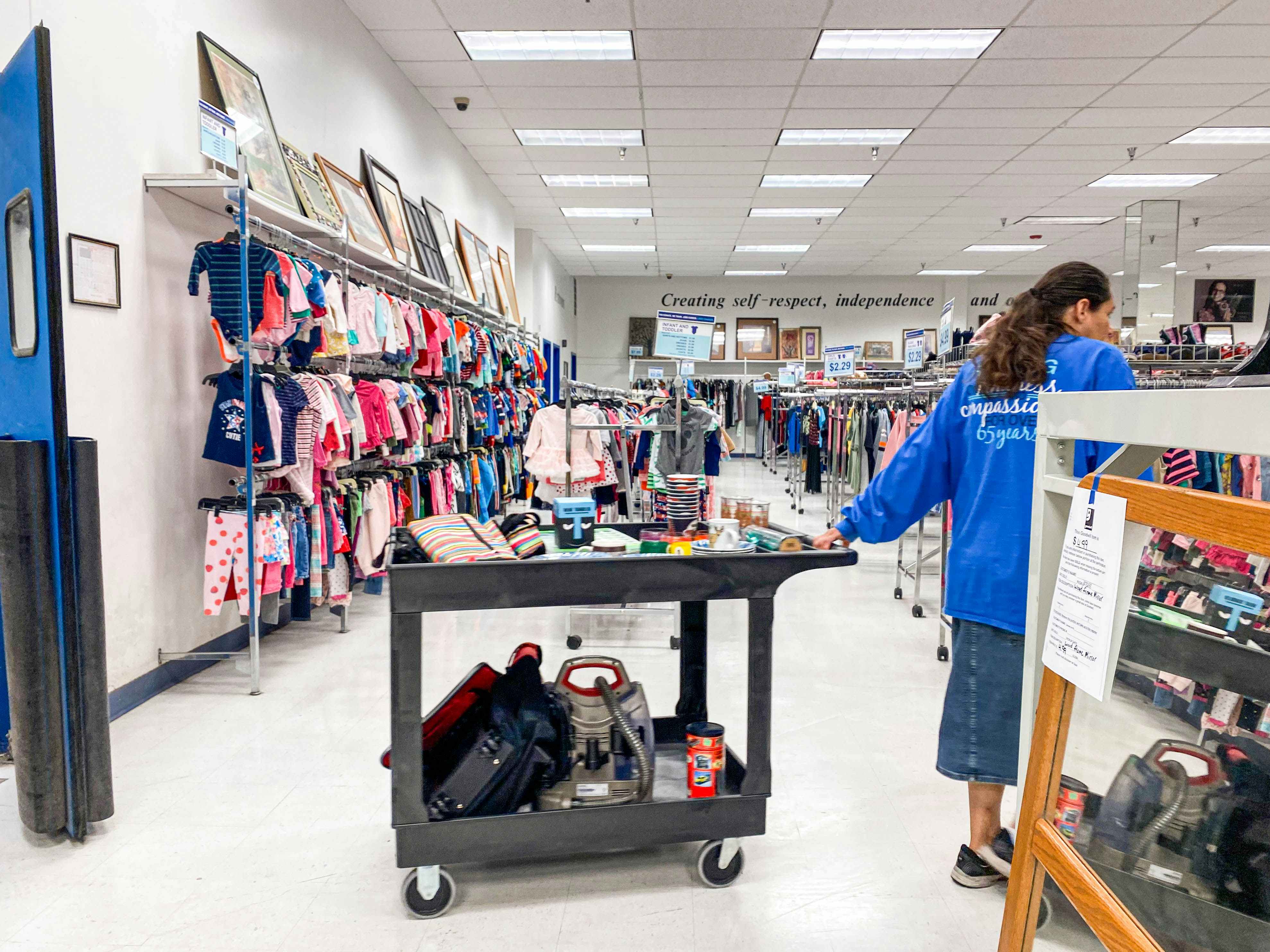 a goodwill employee with a cart of items to restock store
