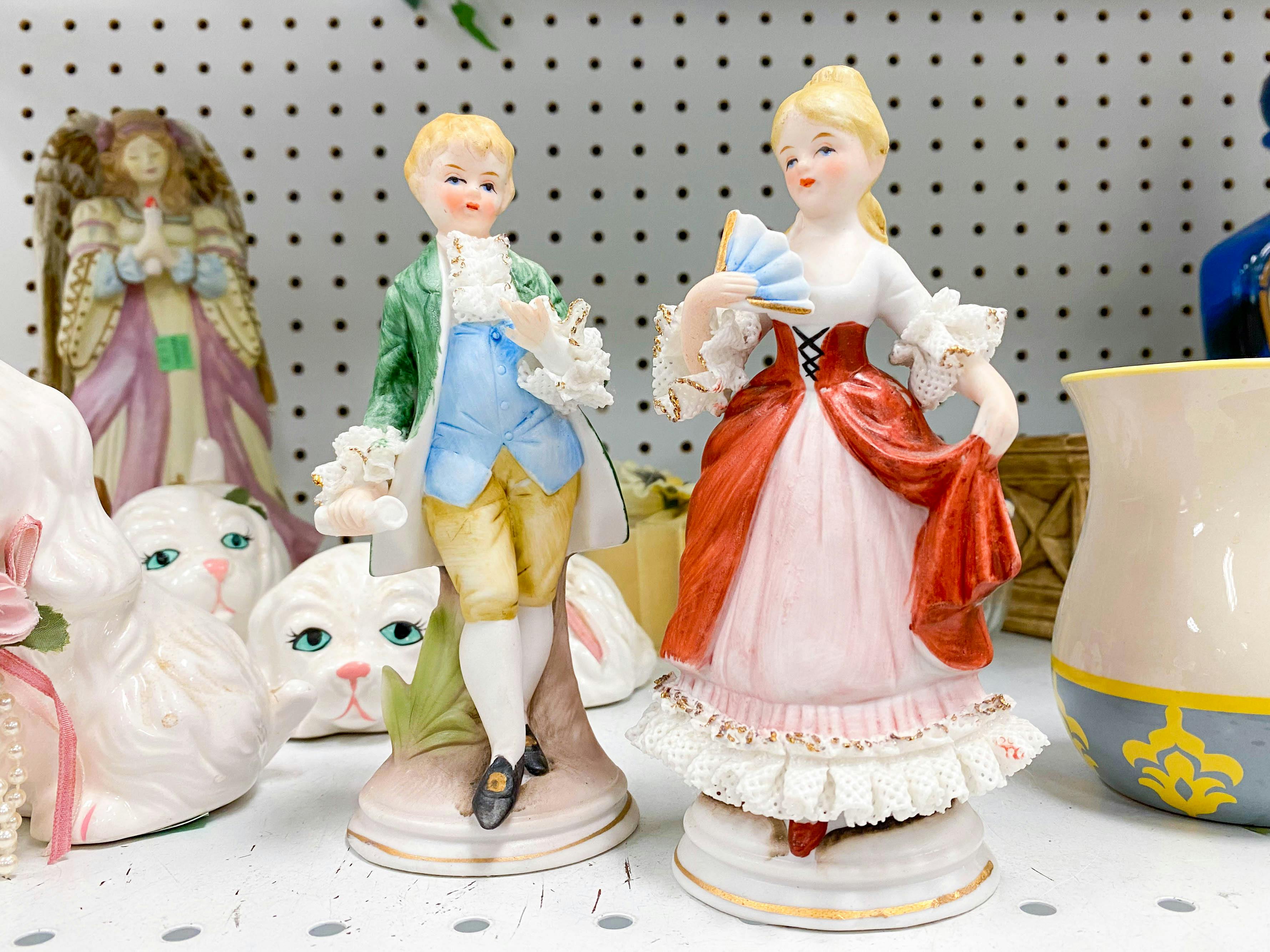 vintage boy and girl porcelain figurines on thrift store shelf