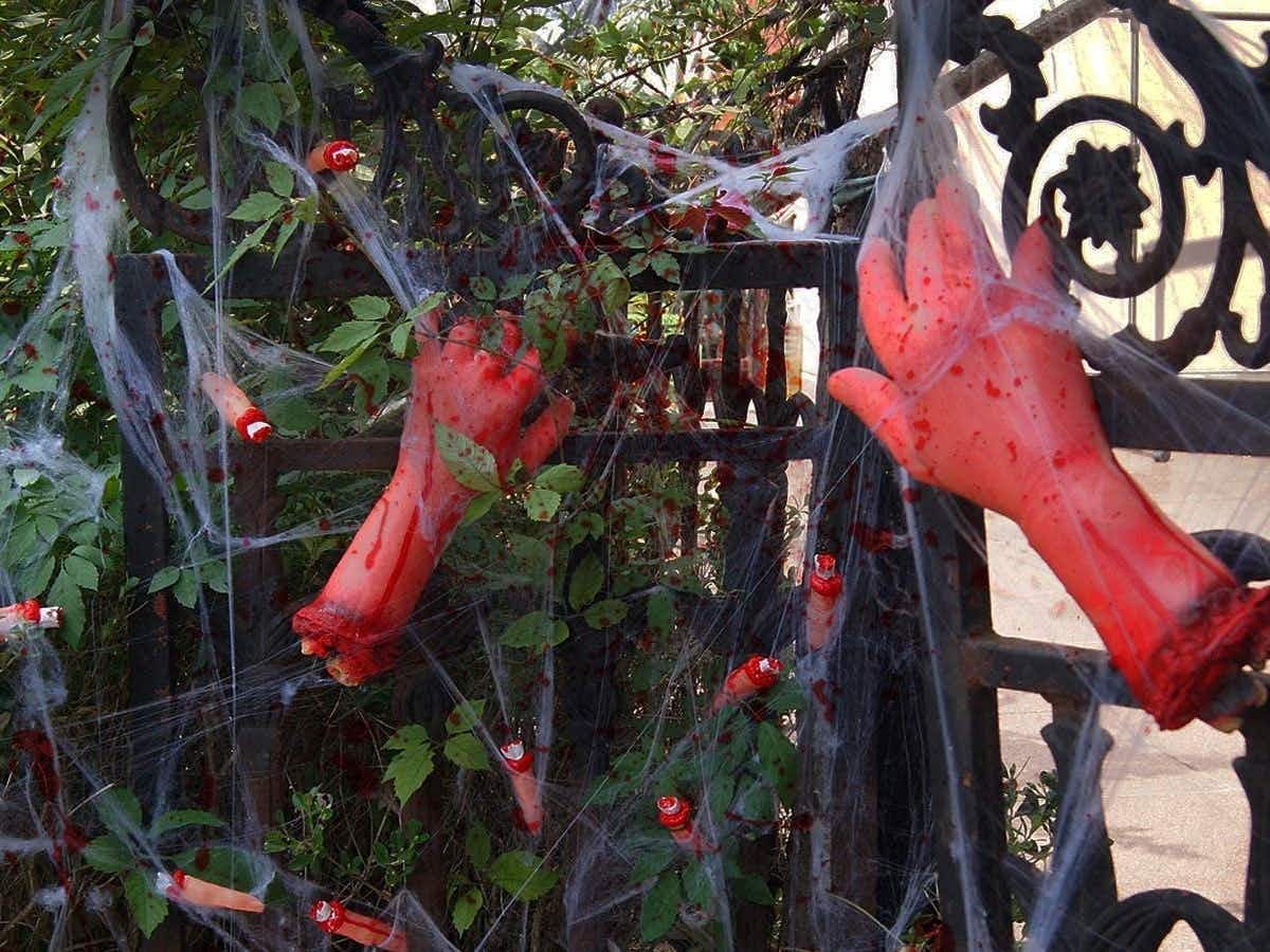 Fake bloodied hands put up around some metal fencing for Halloween decor.