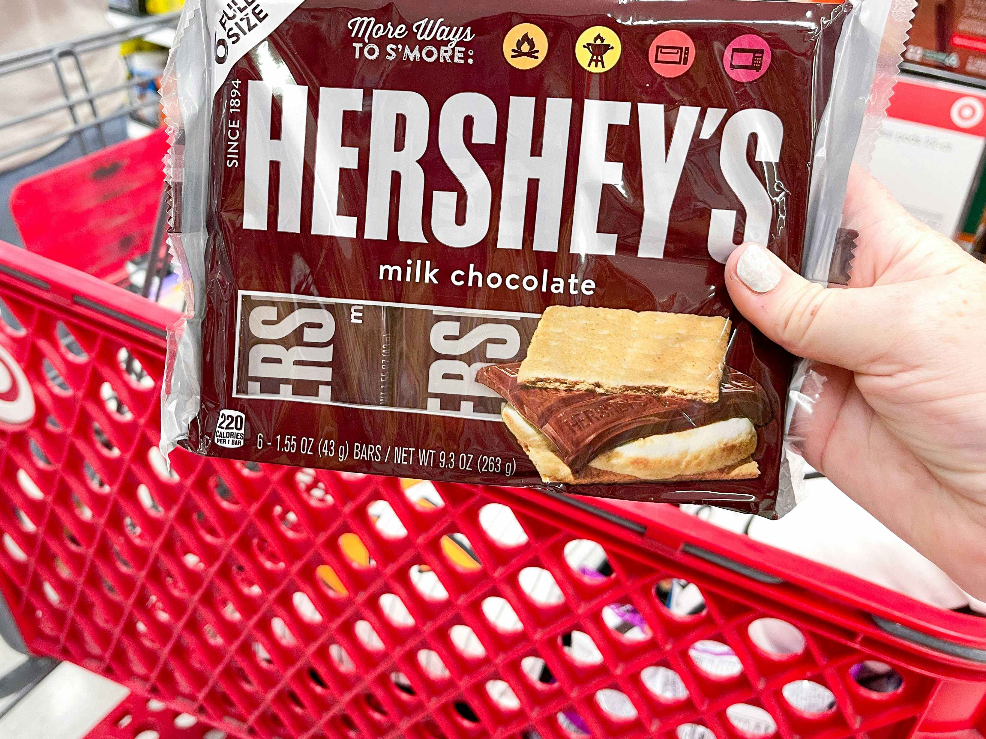 a person holding hersheys in store by cart
