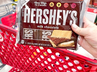 a person holding hersheys in store by cart
