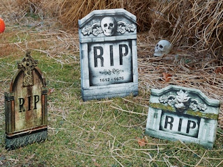 Three fake gravestones decorating a front lawn.