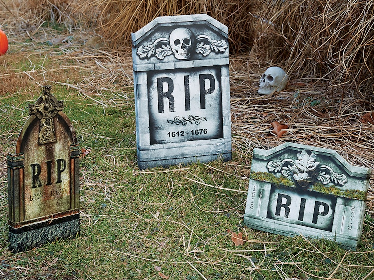 Three fake gravestones decorating a front lawn.