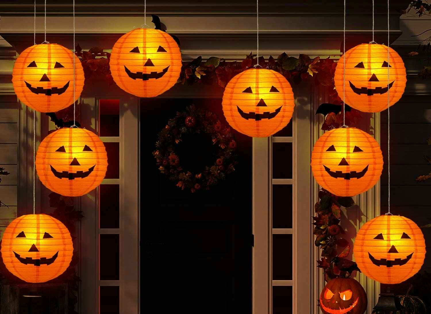 Orange Jack-O-Lantern Halloween paper lanterns strung up to decorate a front porch.