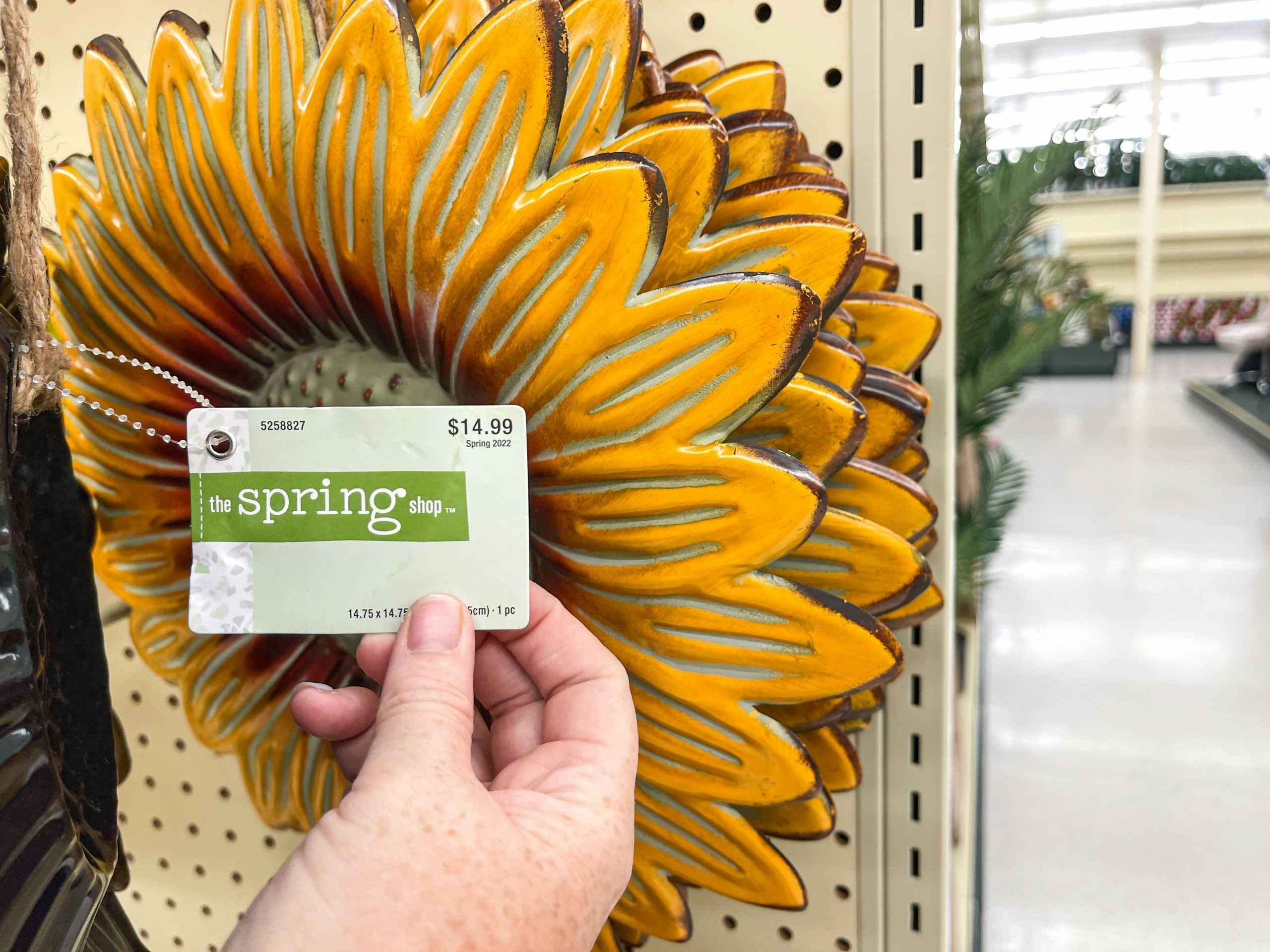 someone looking at the pricetag of a large metal sunflower 