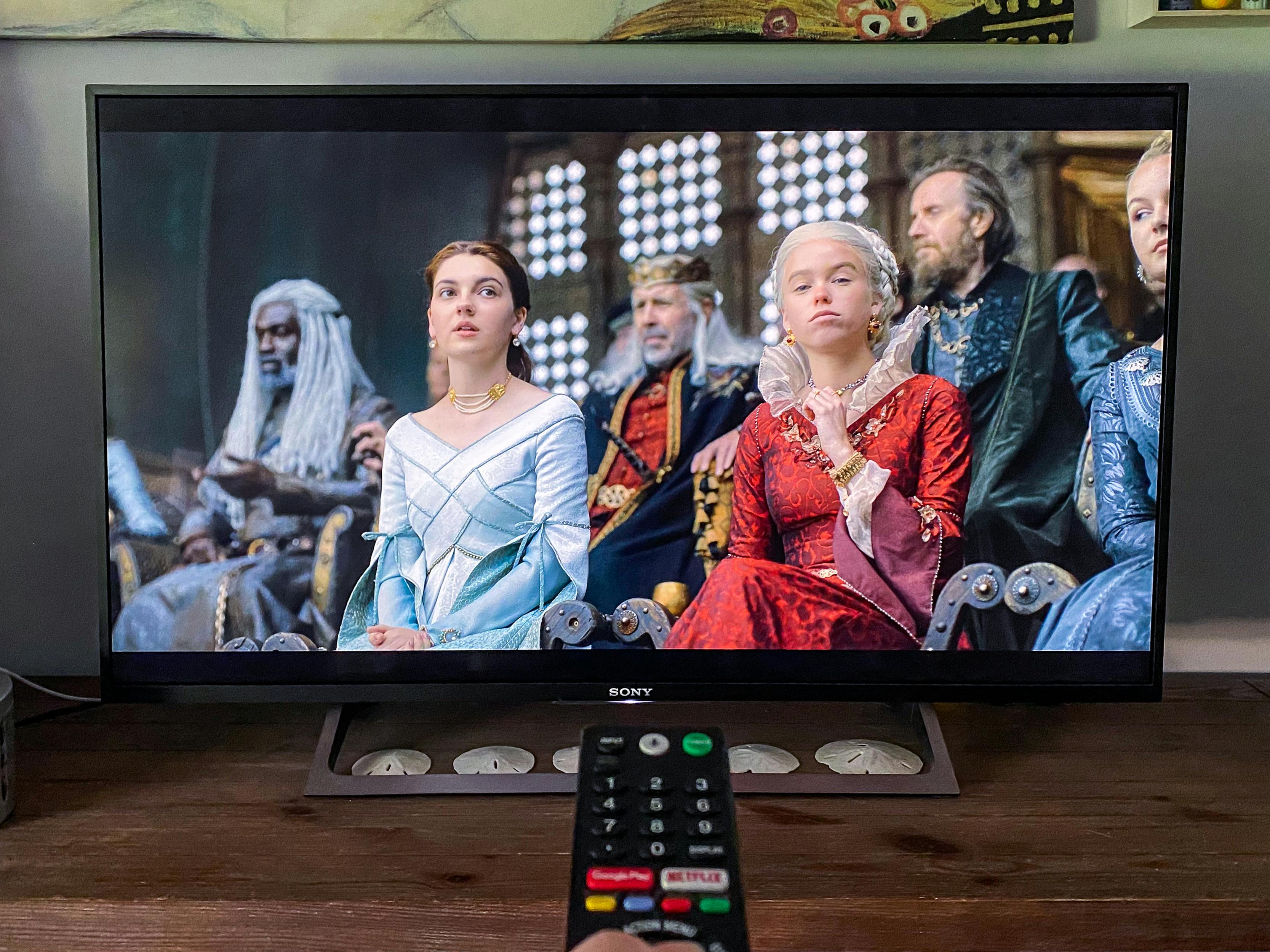 A remote being pointed at a TV playing the first episode of House of the Dragon on HBO.