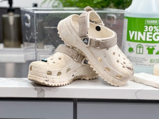 A pair of dirty Crocs on a counter next to a sink.