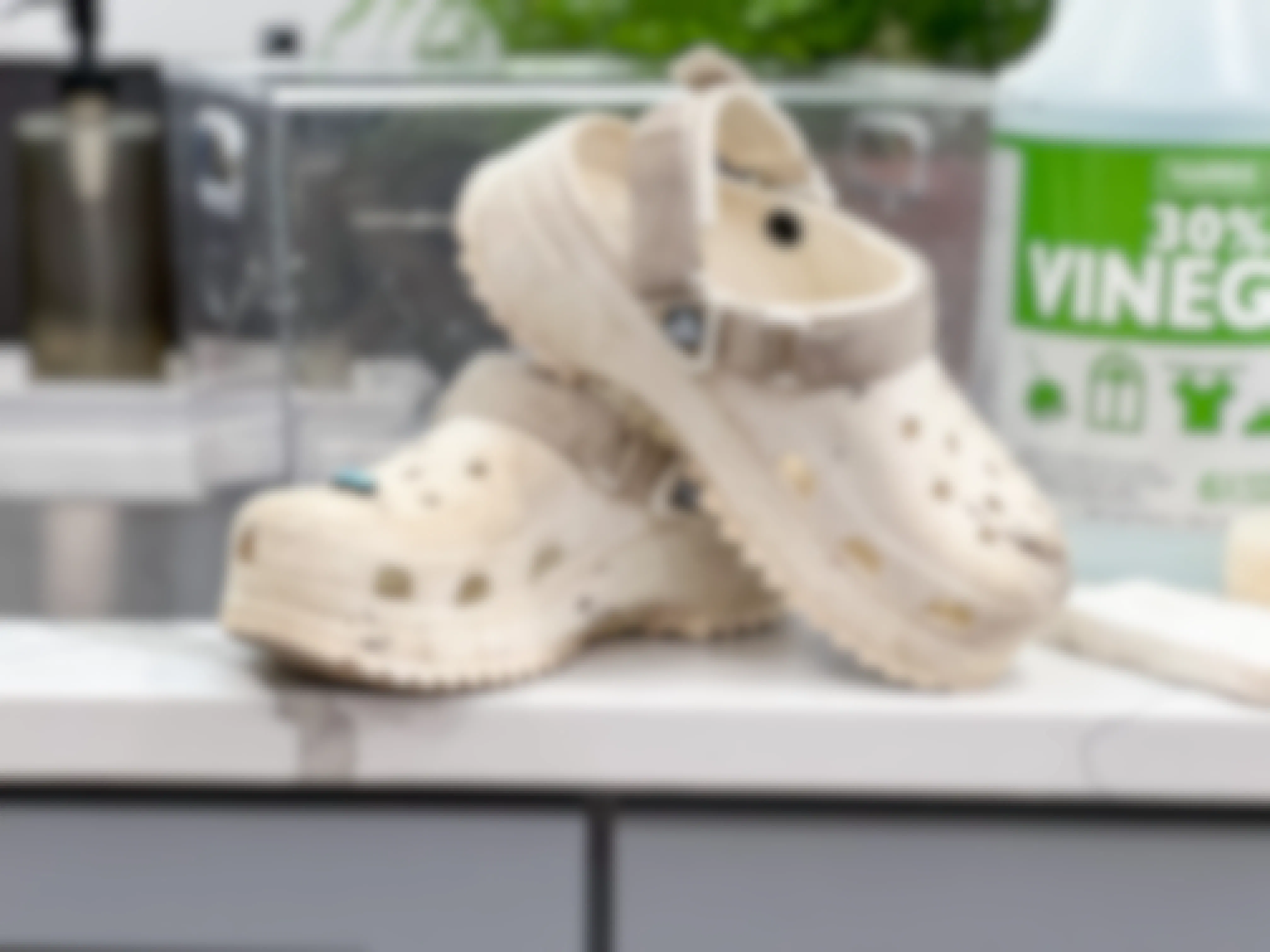 A pair of dirty Crocs on a counter next to a sink.