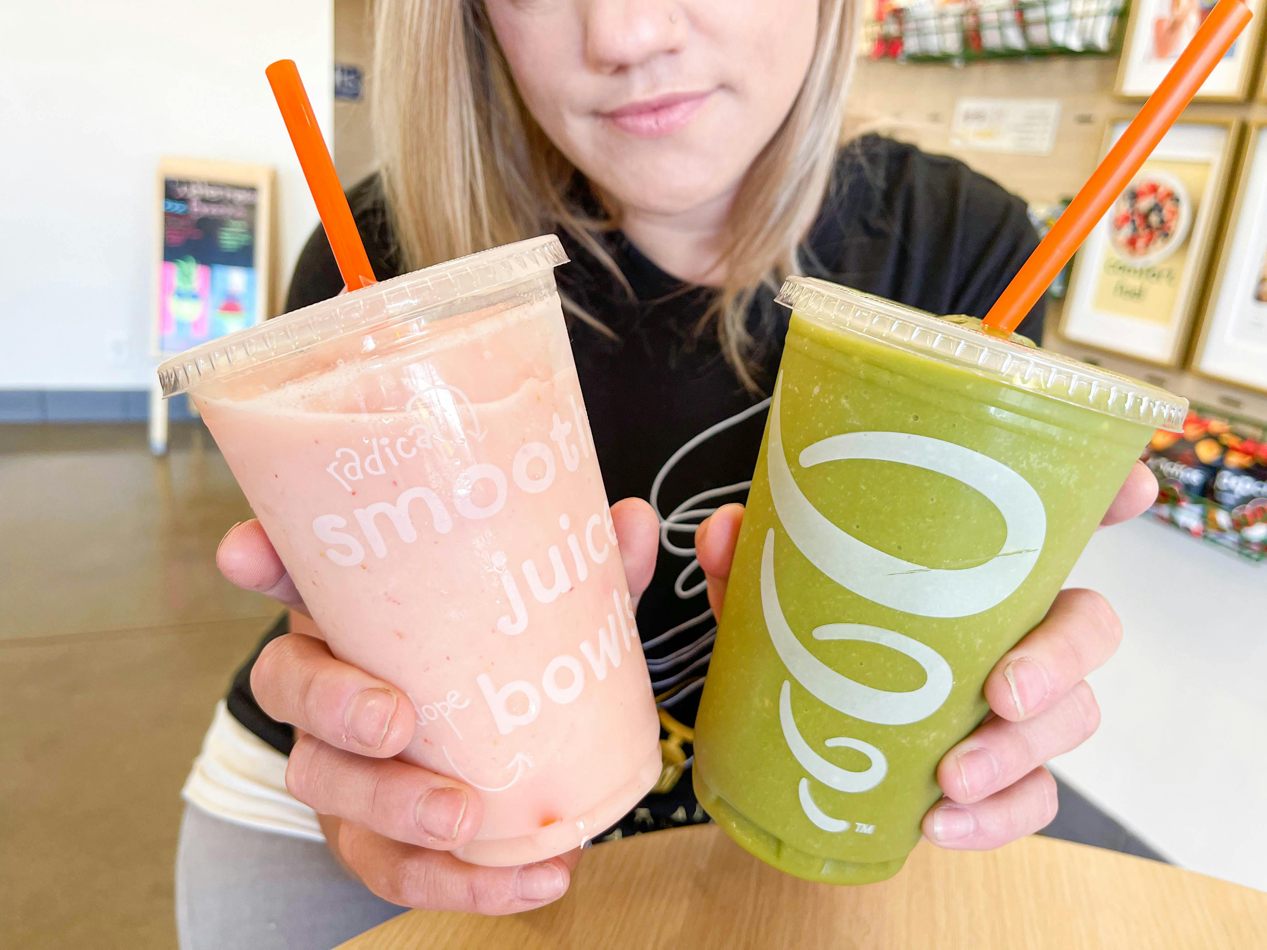 woman holding two smoothies on table