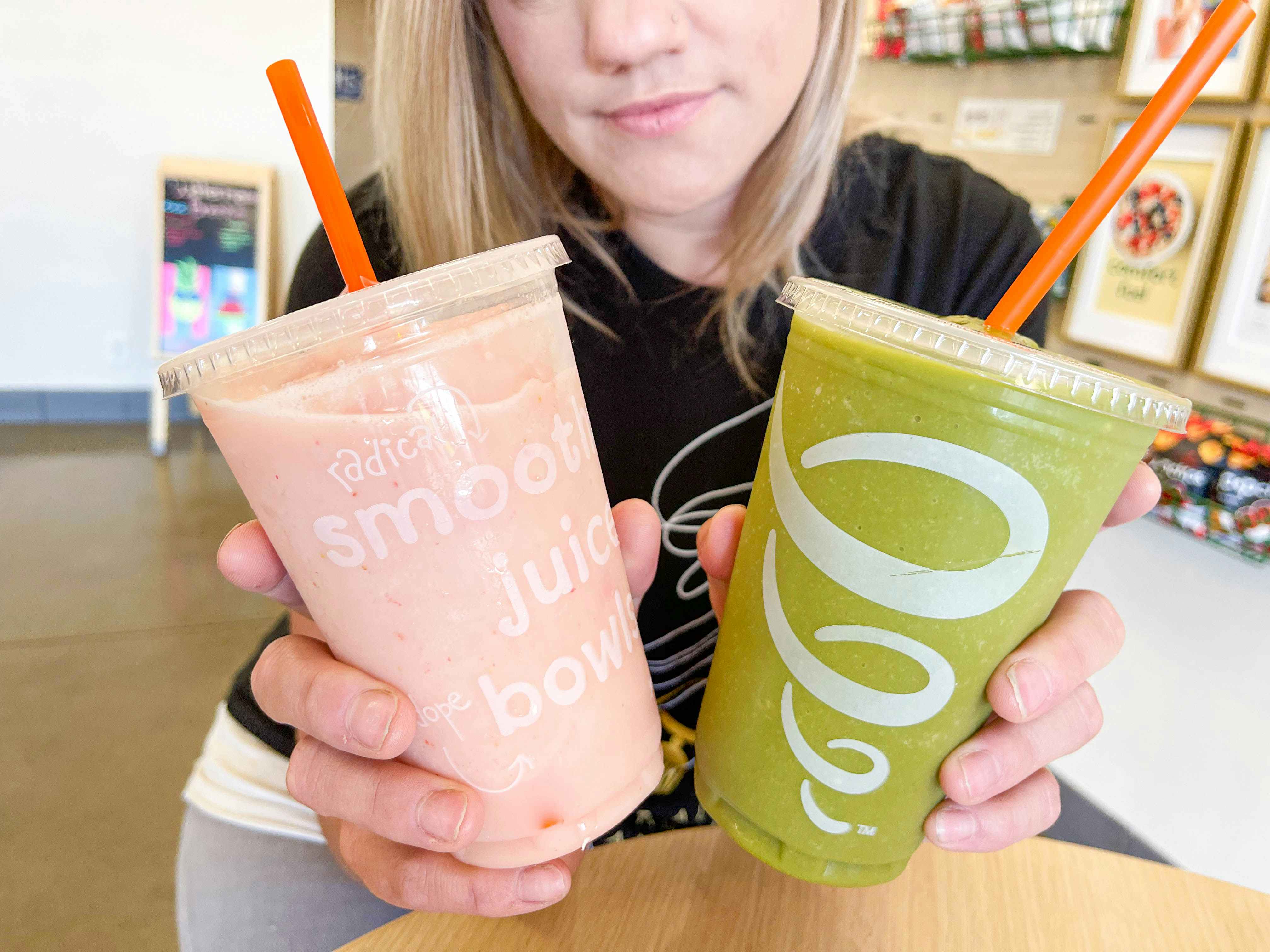 person holding two smoothies on table