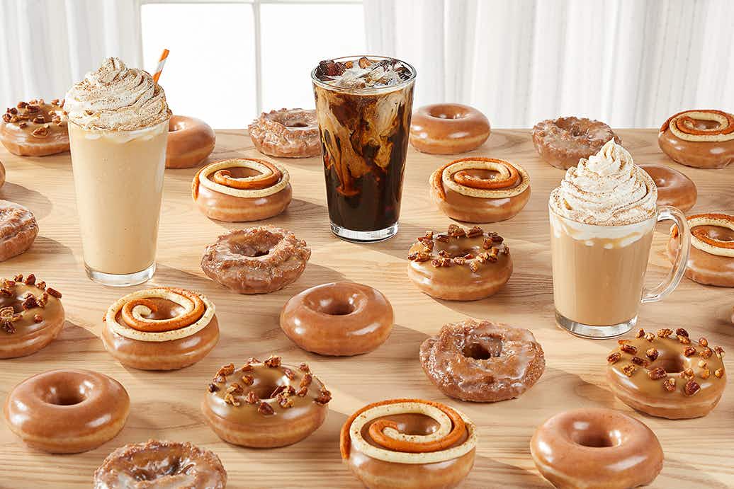 pumpkin spice drinks and doughnuts from Krispy Kreme laid out on a table