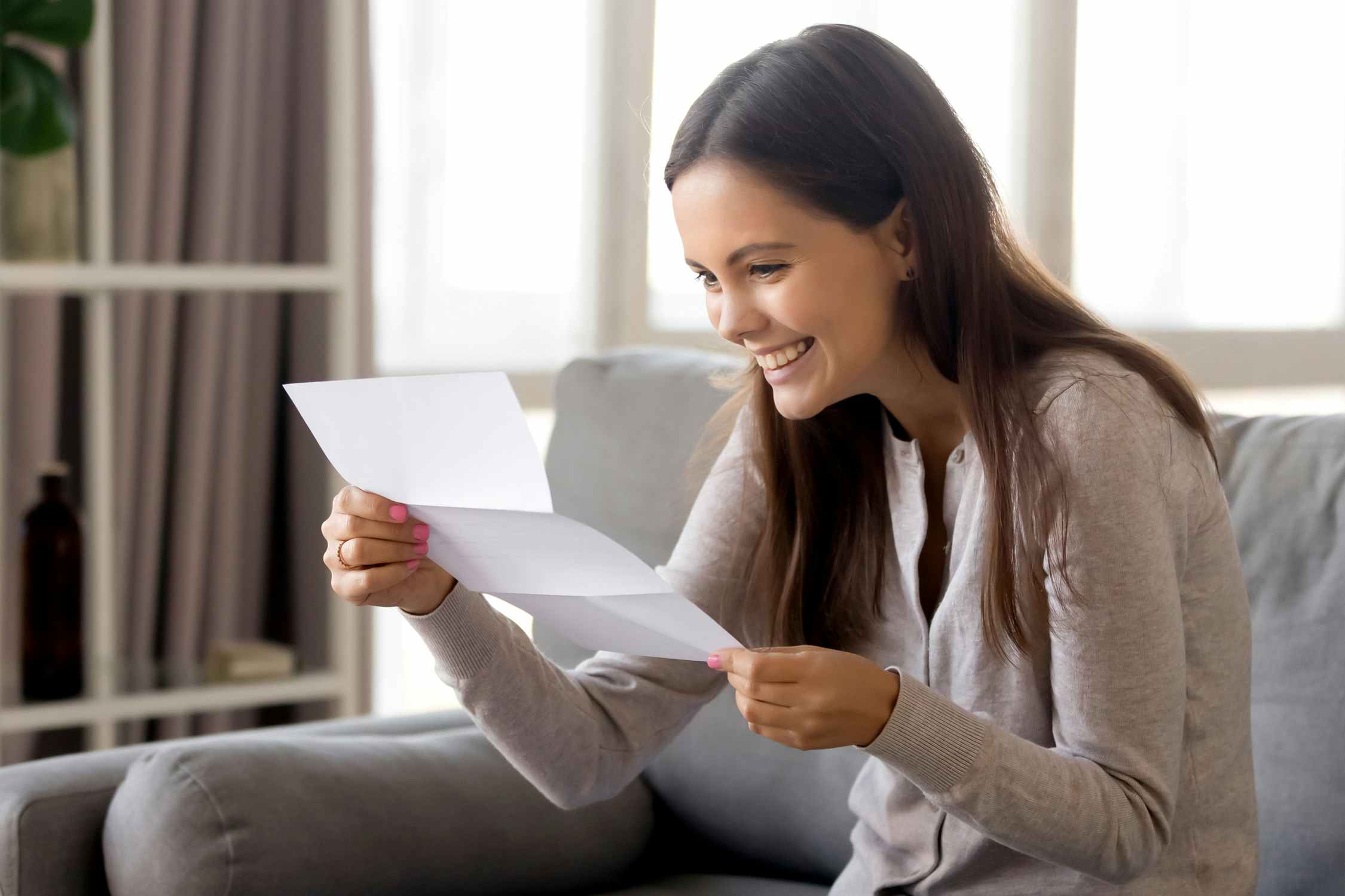 happy woman smiling and holding letter in home