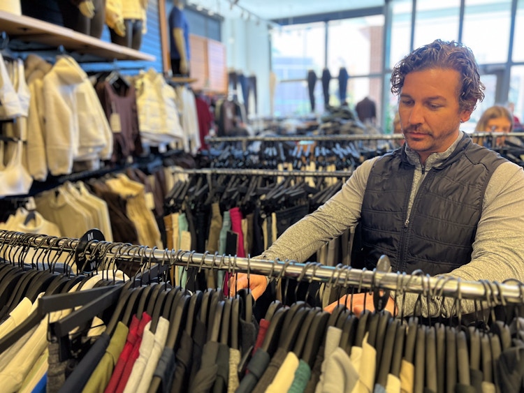 model sifting through clothing rack
