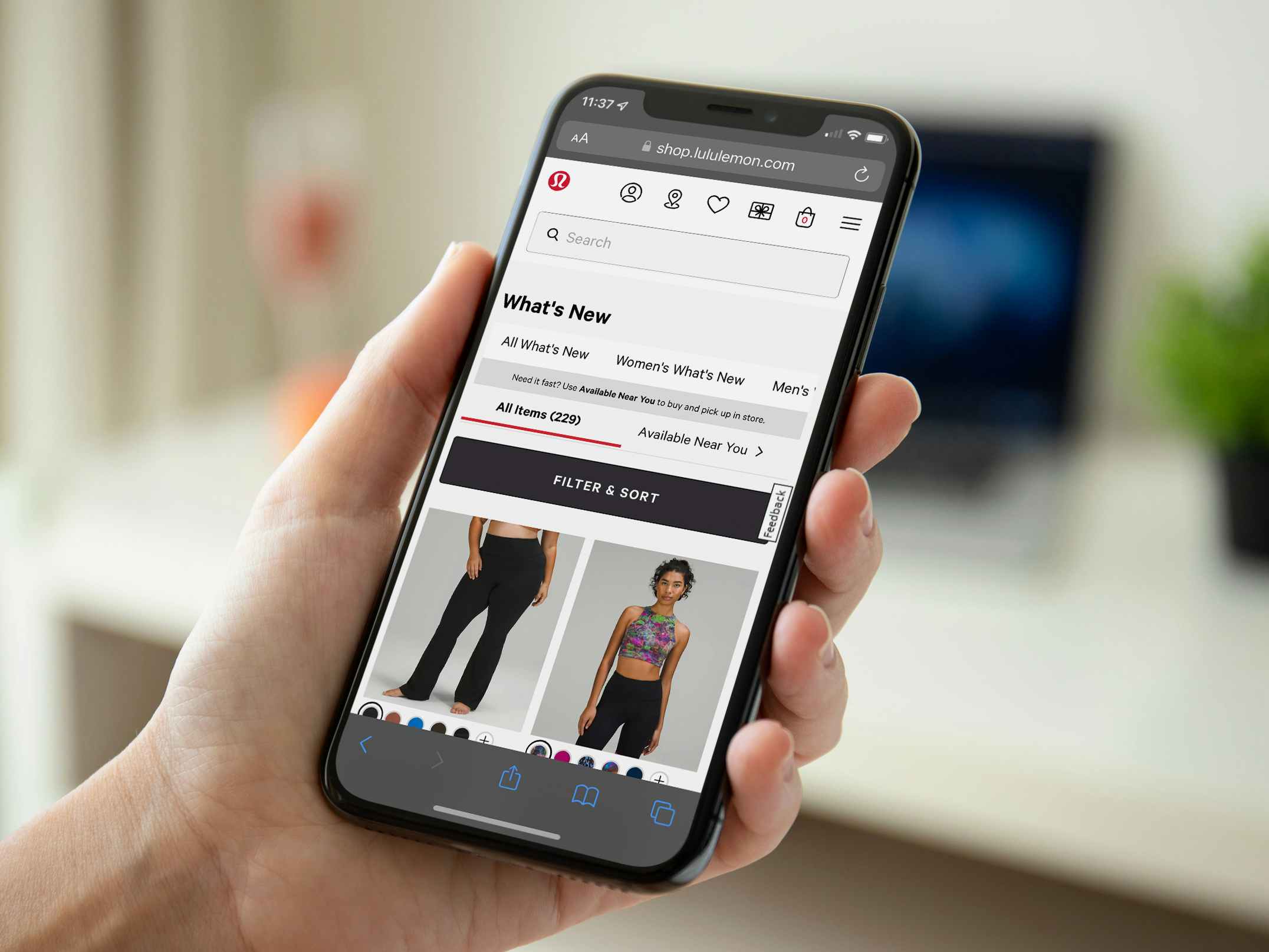 A person holding a phone displaying the What's New page on the Lululemon website.