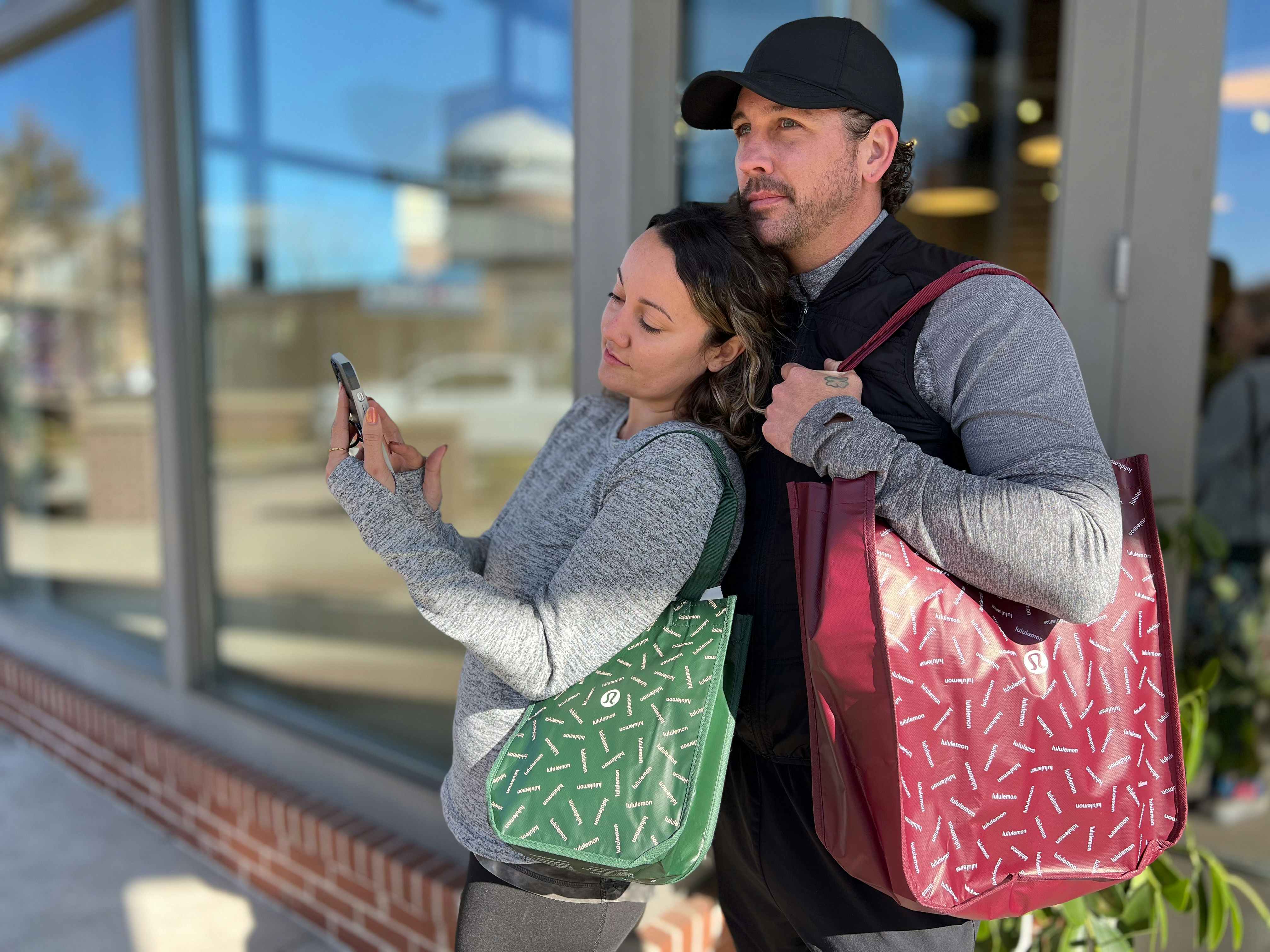 couple outside lululemon store on cell phone holding bags