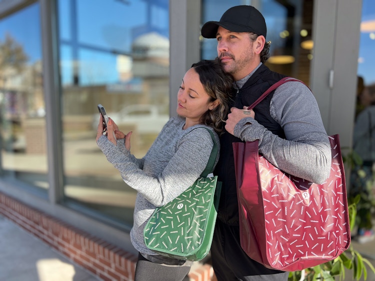 couple outside lululemon store on cell phone holding bags