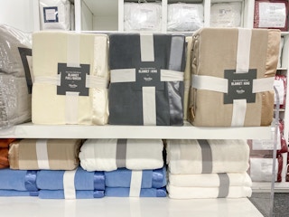 Martha Stewart Fleece blankets in khaki, cream, and dark grey on a shelf