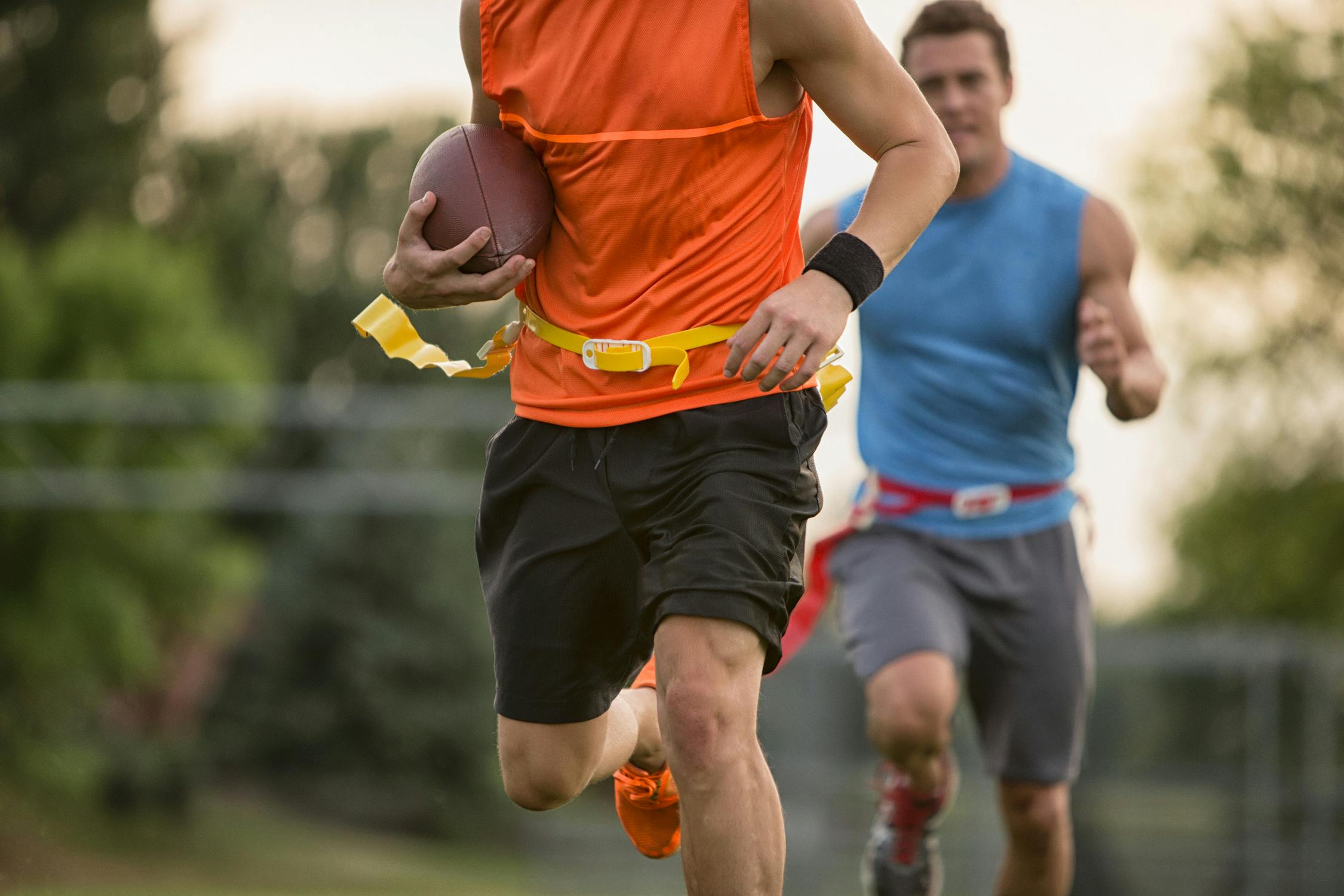 men running and playing flag football outside