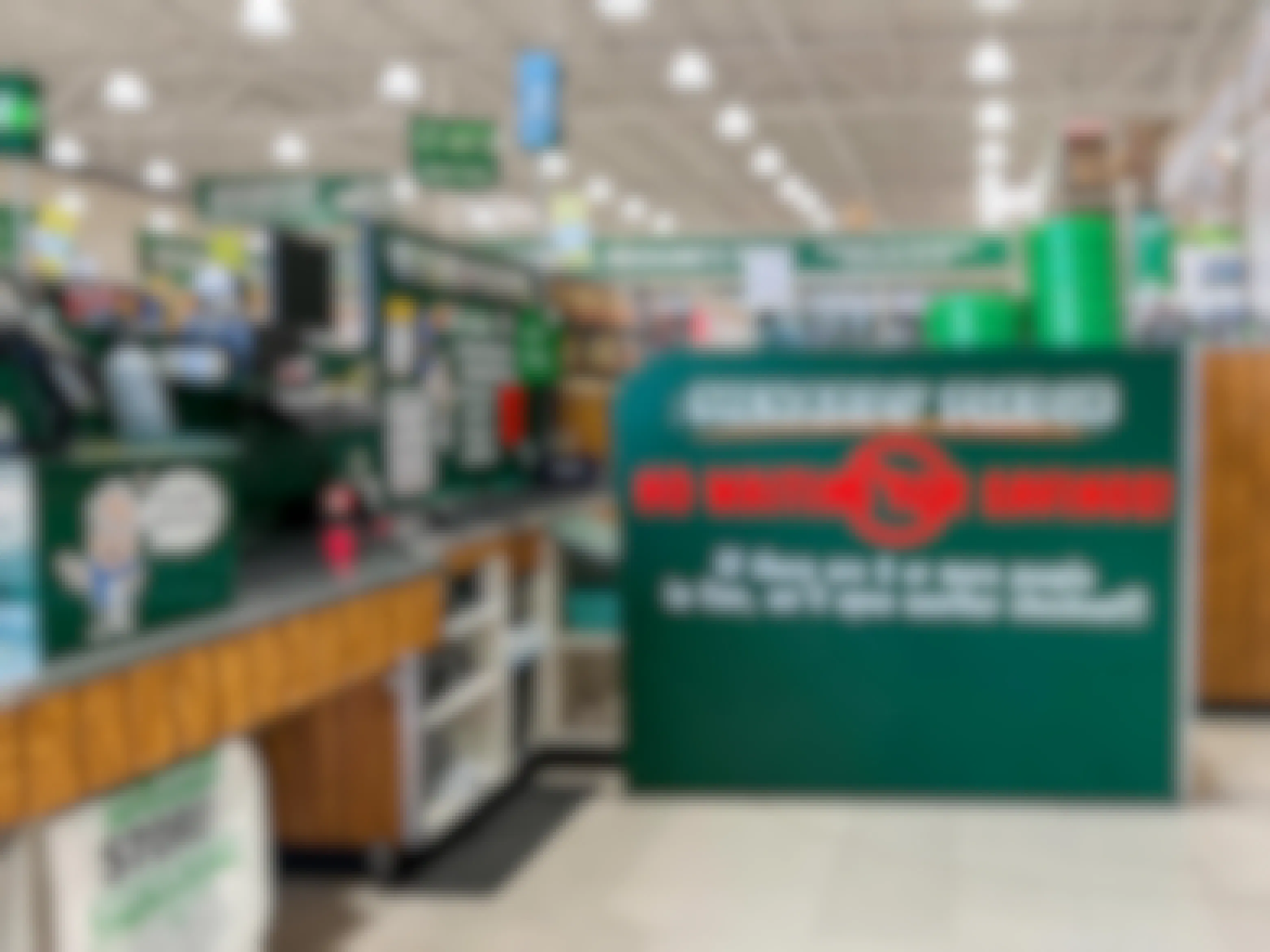 A large sign near a Menards checkout lane that reads, "Menards Pledge: No Waiting for Savings. If there are 2 or more people in line, we will open another checkout!!