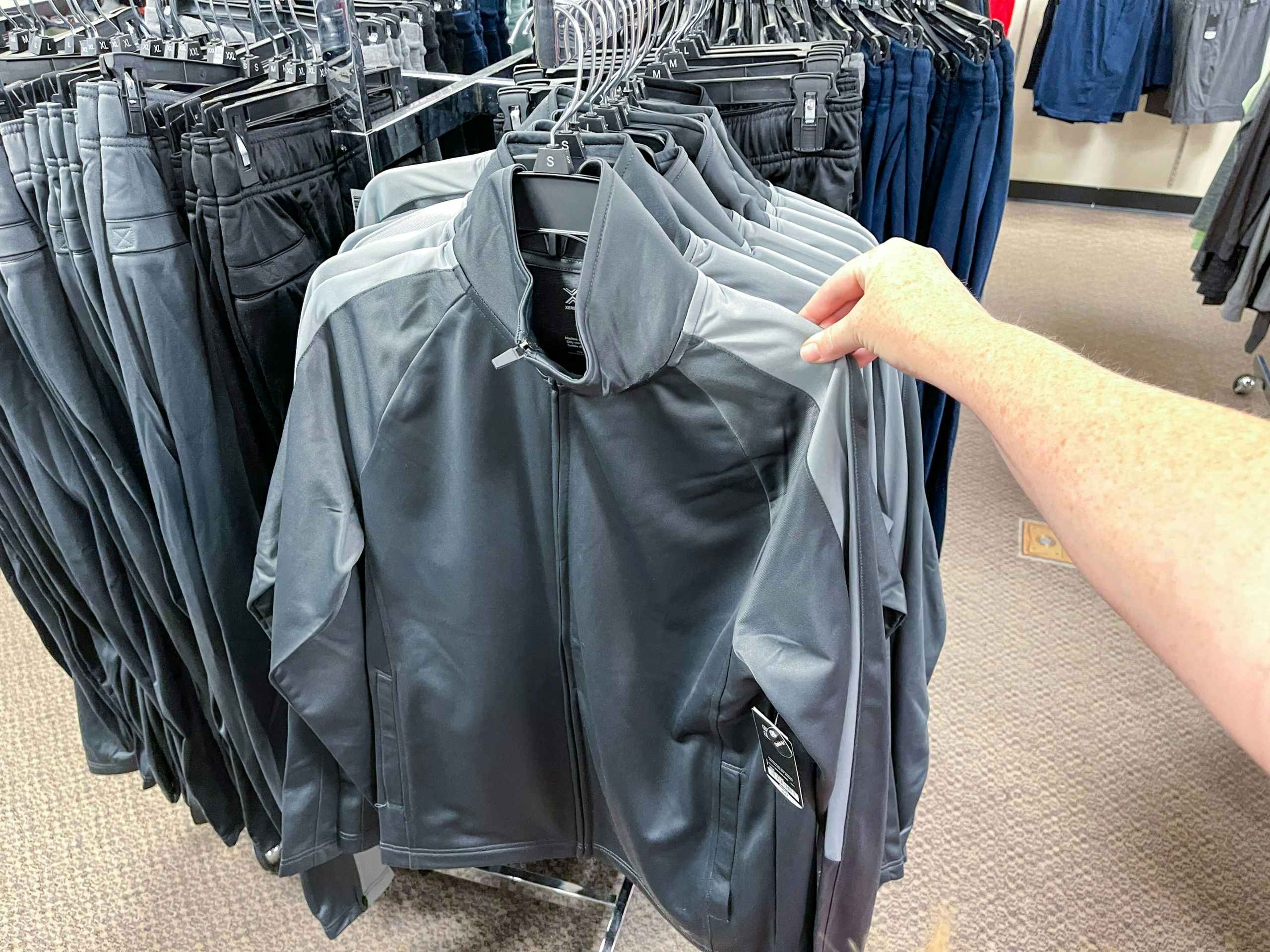 someone touching a mens jacket hanging on a rack