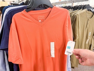 someone holding the tag to a mens orange shirt