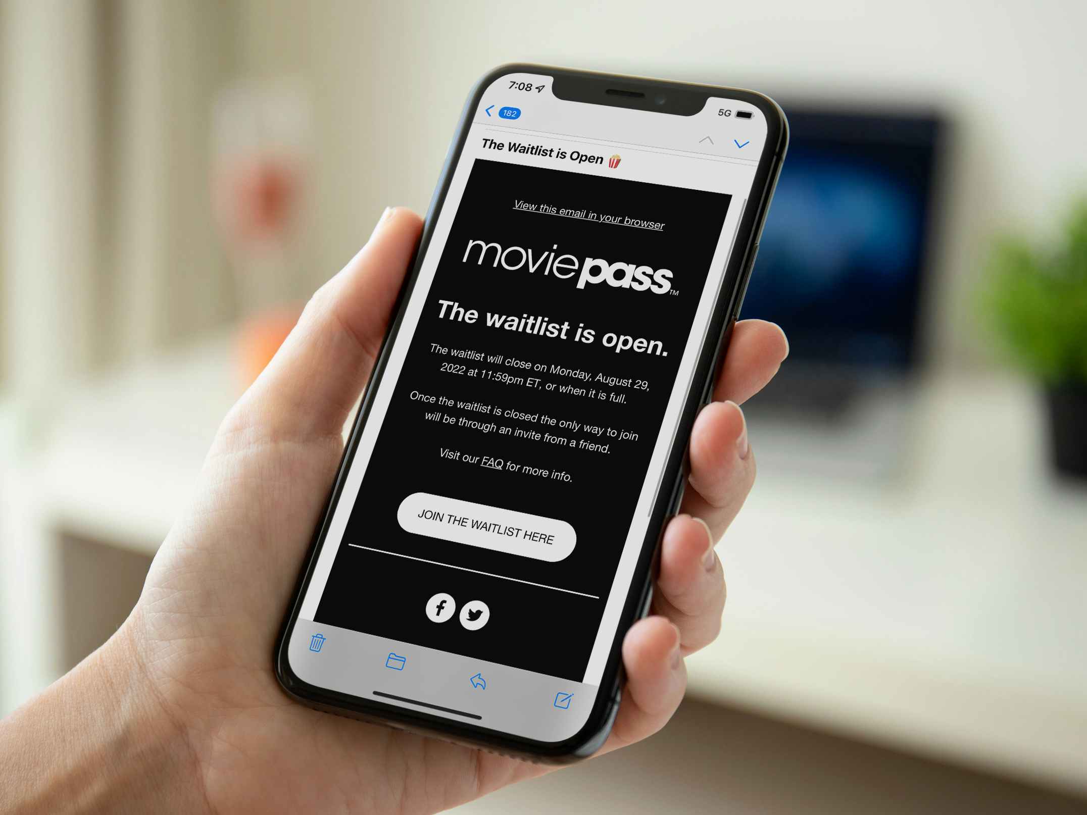 A person's hand holding an iPhone displaying an email from MoviePass stating that the waitlist is open.