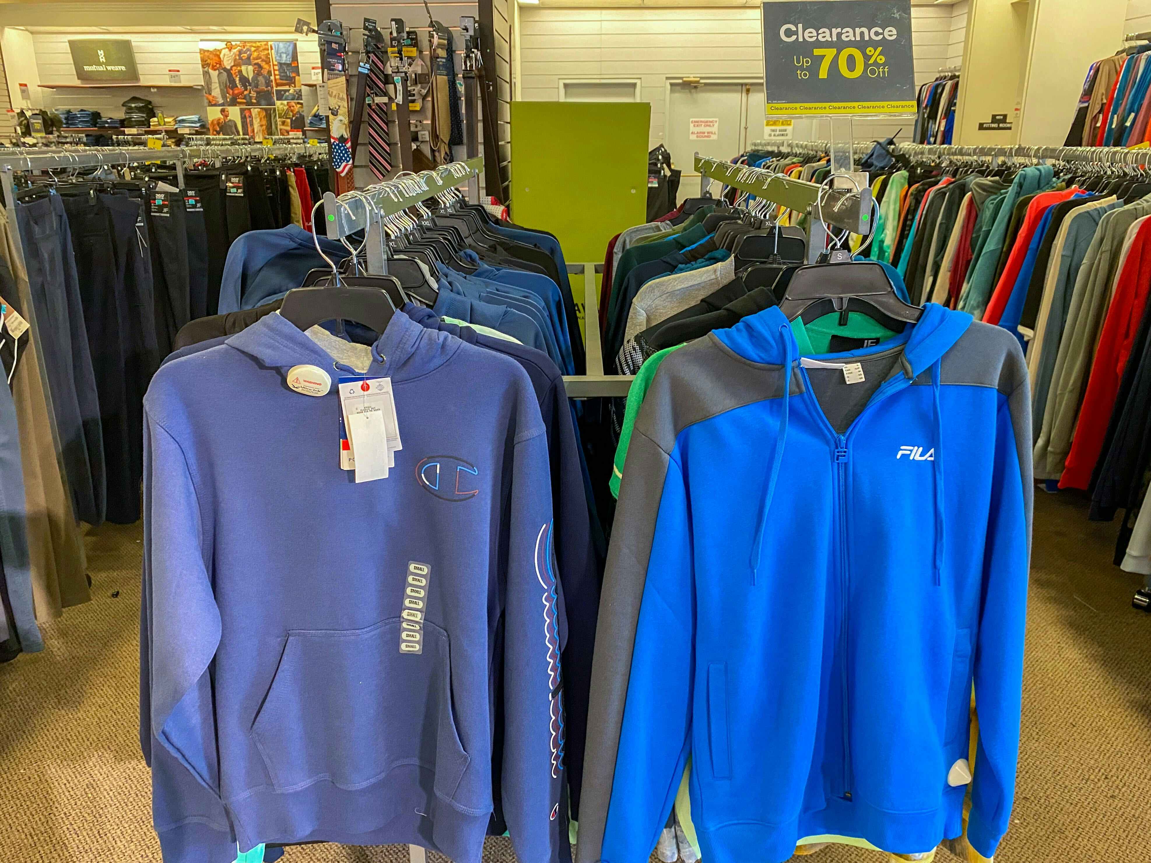 a blue champion and a blue fila sweatshirt by a clearance sign