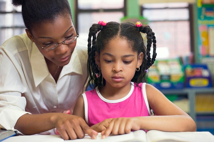 NEA Foundation female teacher helping student book