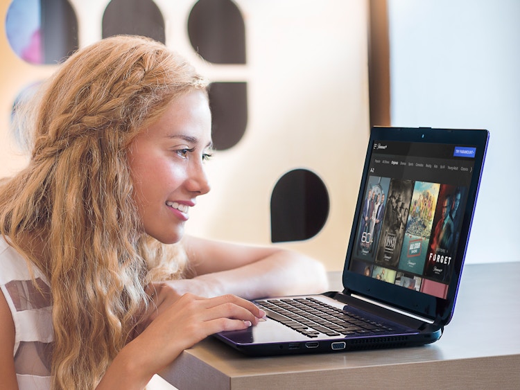 Woman looking at computer looking at. different titles on Paramount Plus