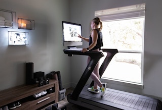 Woman using the Peloton Tread exercise equipment
