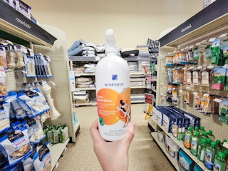 hand holding a bottle of bioesque urine neutralizer spray in an aisle