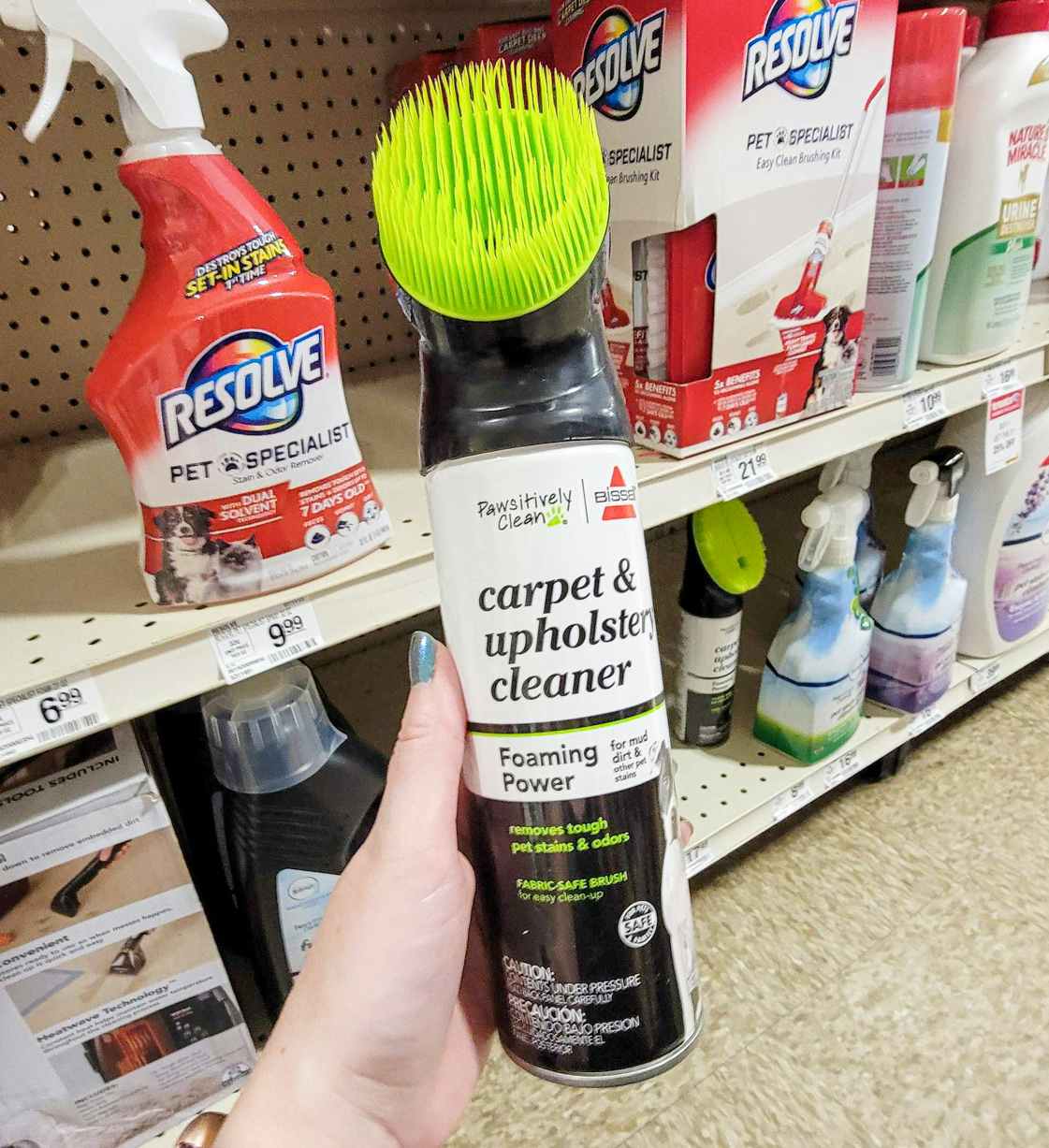 hand holding a bottle of bissell carpet and upholstery cleaner with a brush on it