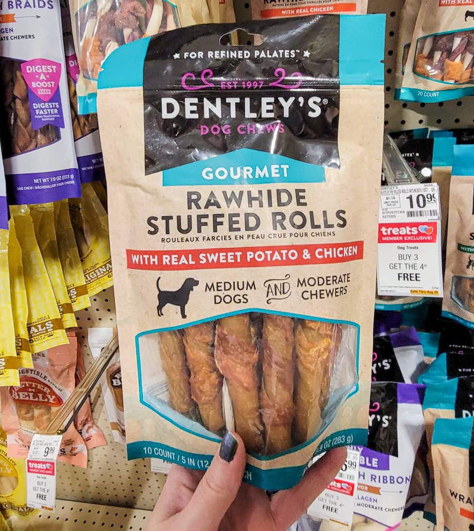 hand holding a bag of dentleys rawhide stuffed rolls dog chews