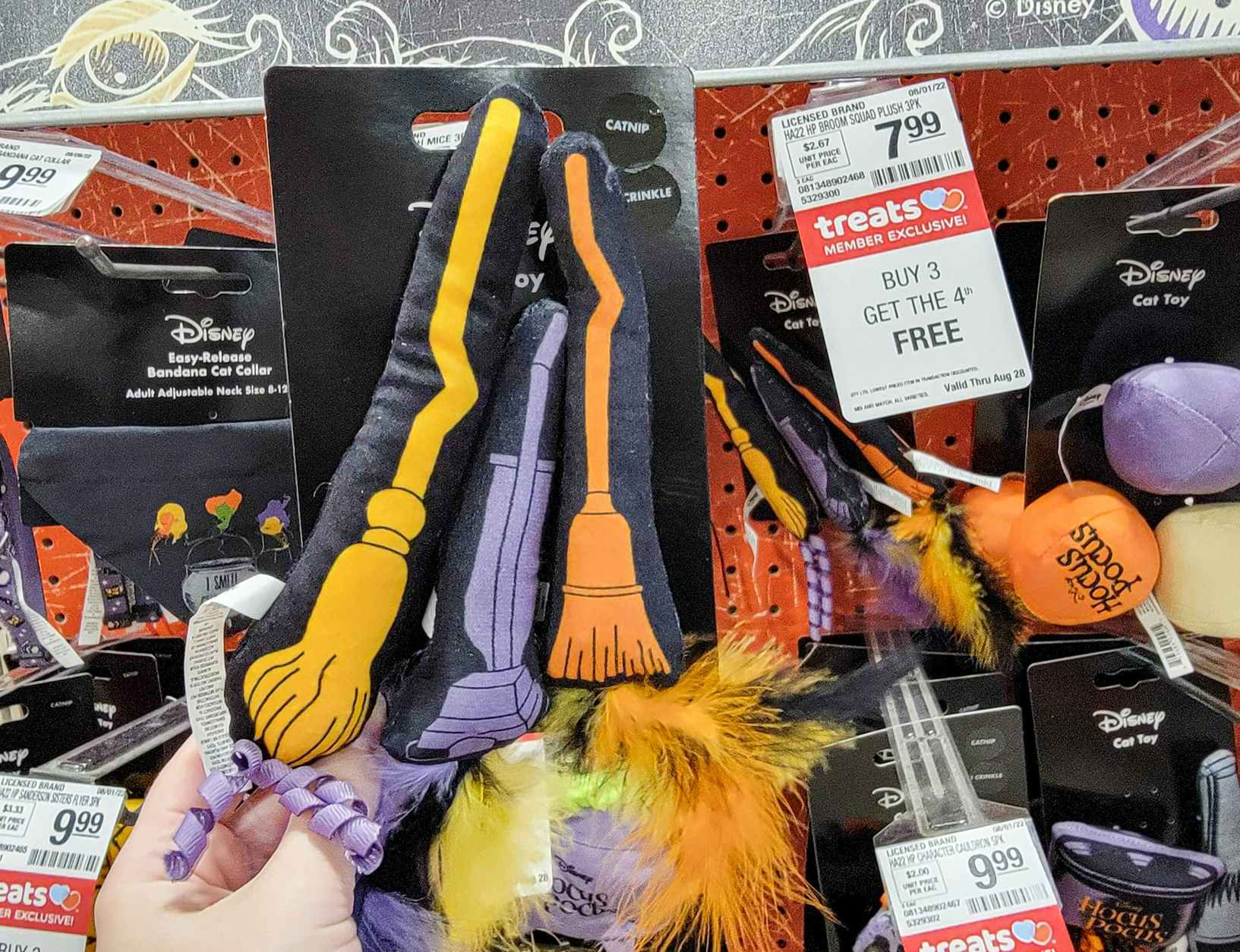 hand holding a 3 pack of hocus pocus broom cat toys