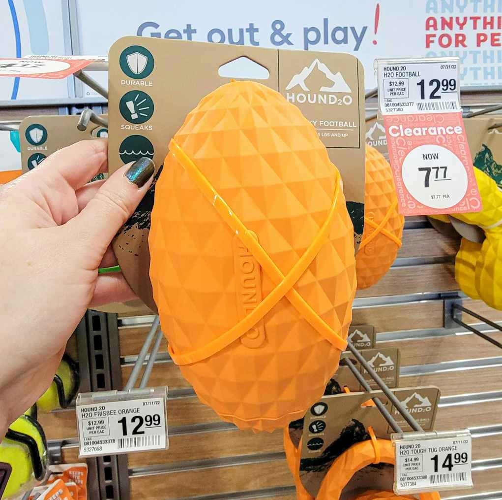 hand holding an orange football dog toy