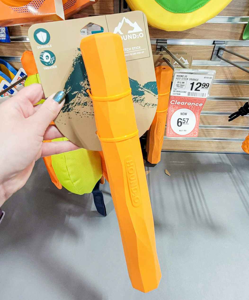 hand holding an orange fetch stick dog toy