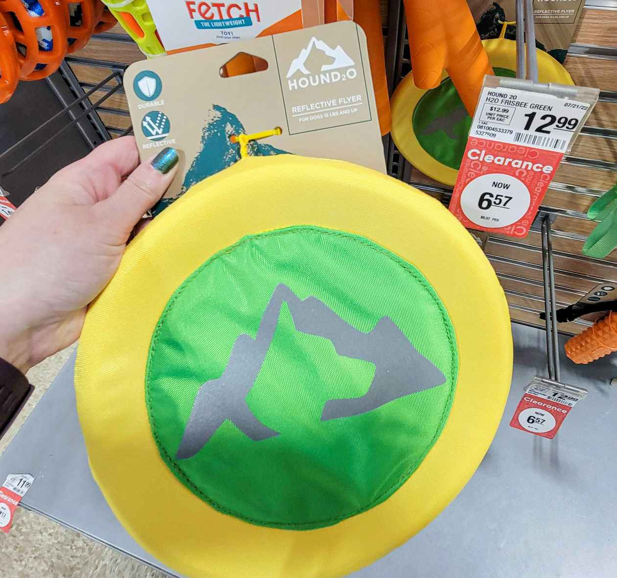 hand holding a green and yellow reflective disc dog toy