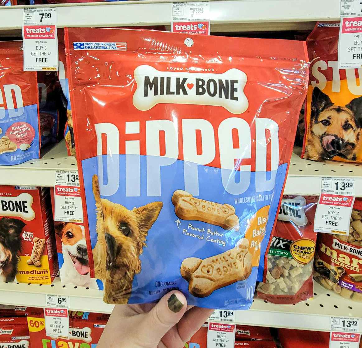 hand holding a bag of milk bone dipped dog treats