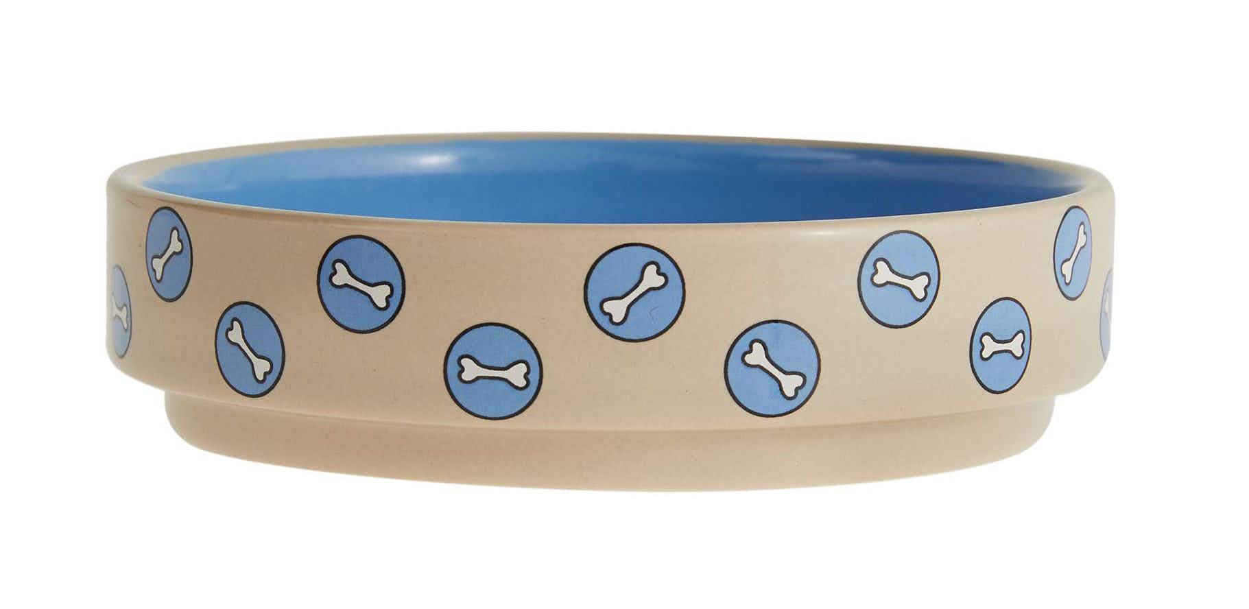 a tan dog bowl with blue circles with bones in them