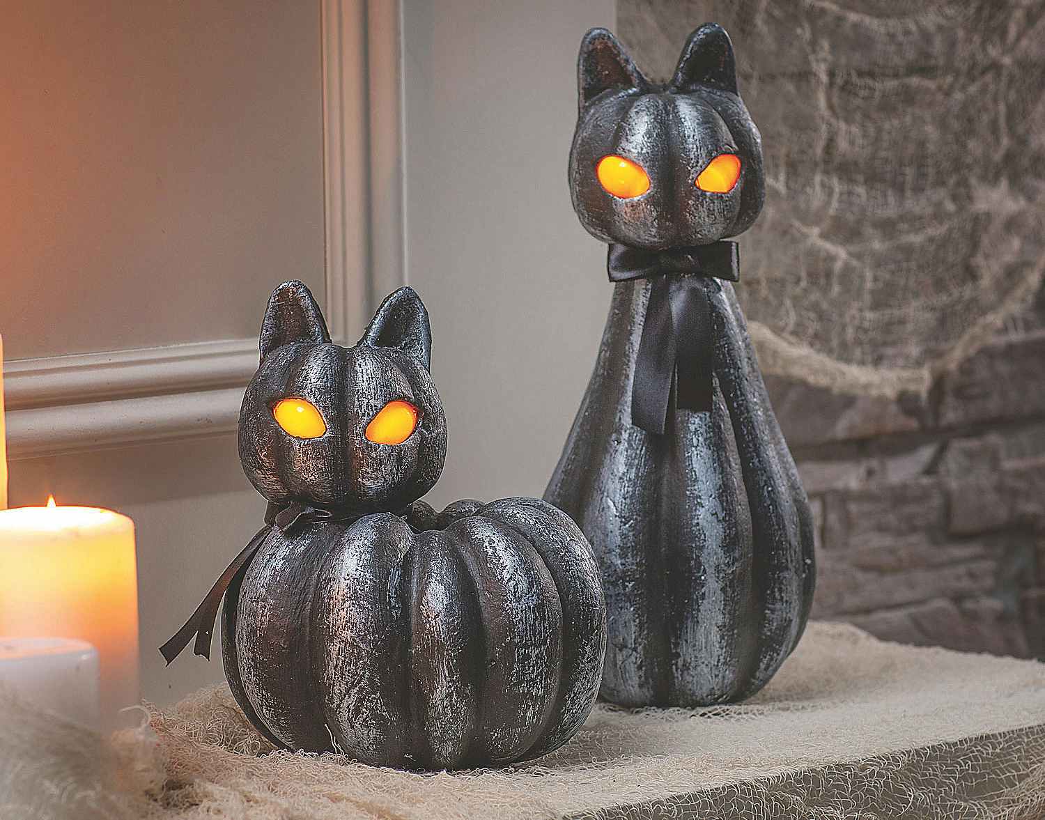 Light-up black cat pumpkin decorations on a table.