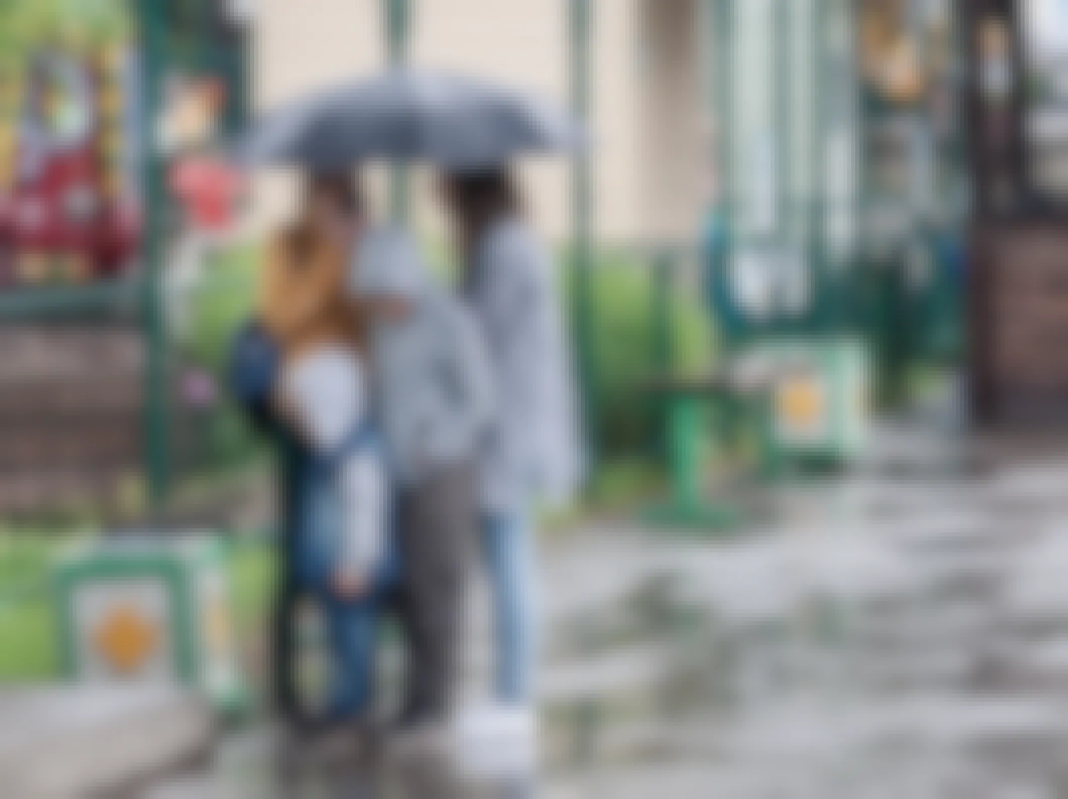 A family grouped under an umbrella on a rainy day at an amusement park.