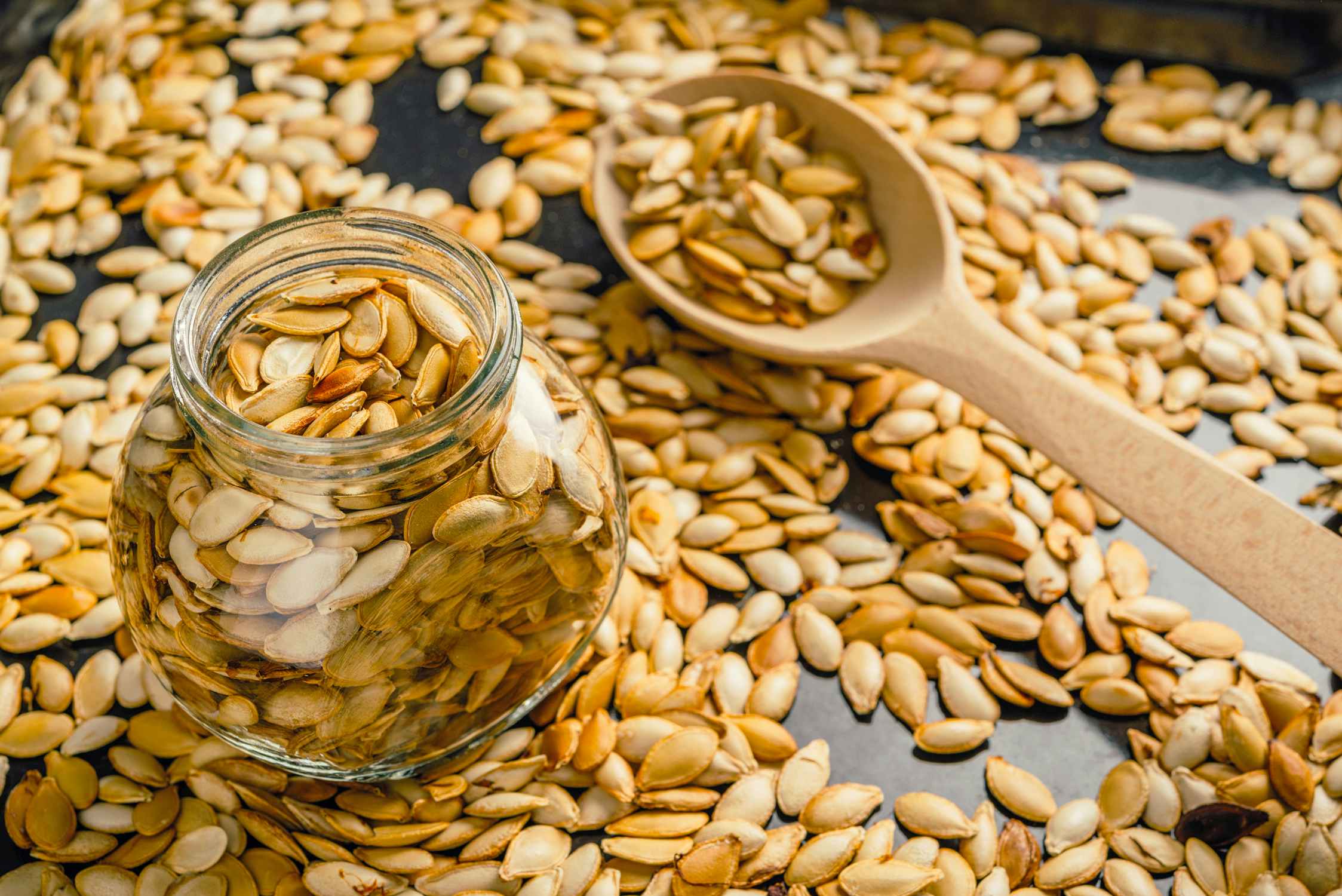 roasted pumpkin seeds on pan, in glass jar, and on spoon