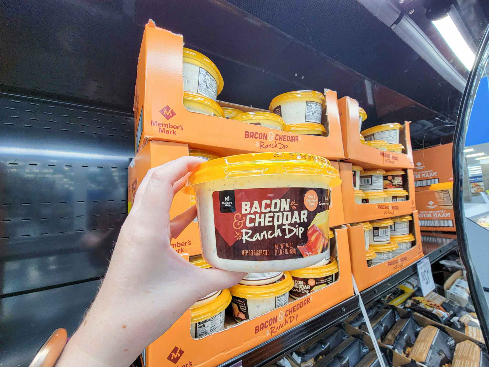 hand holding a container of bacon cheddar ranch dip