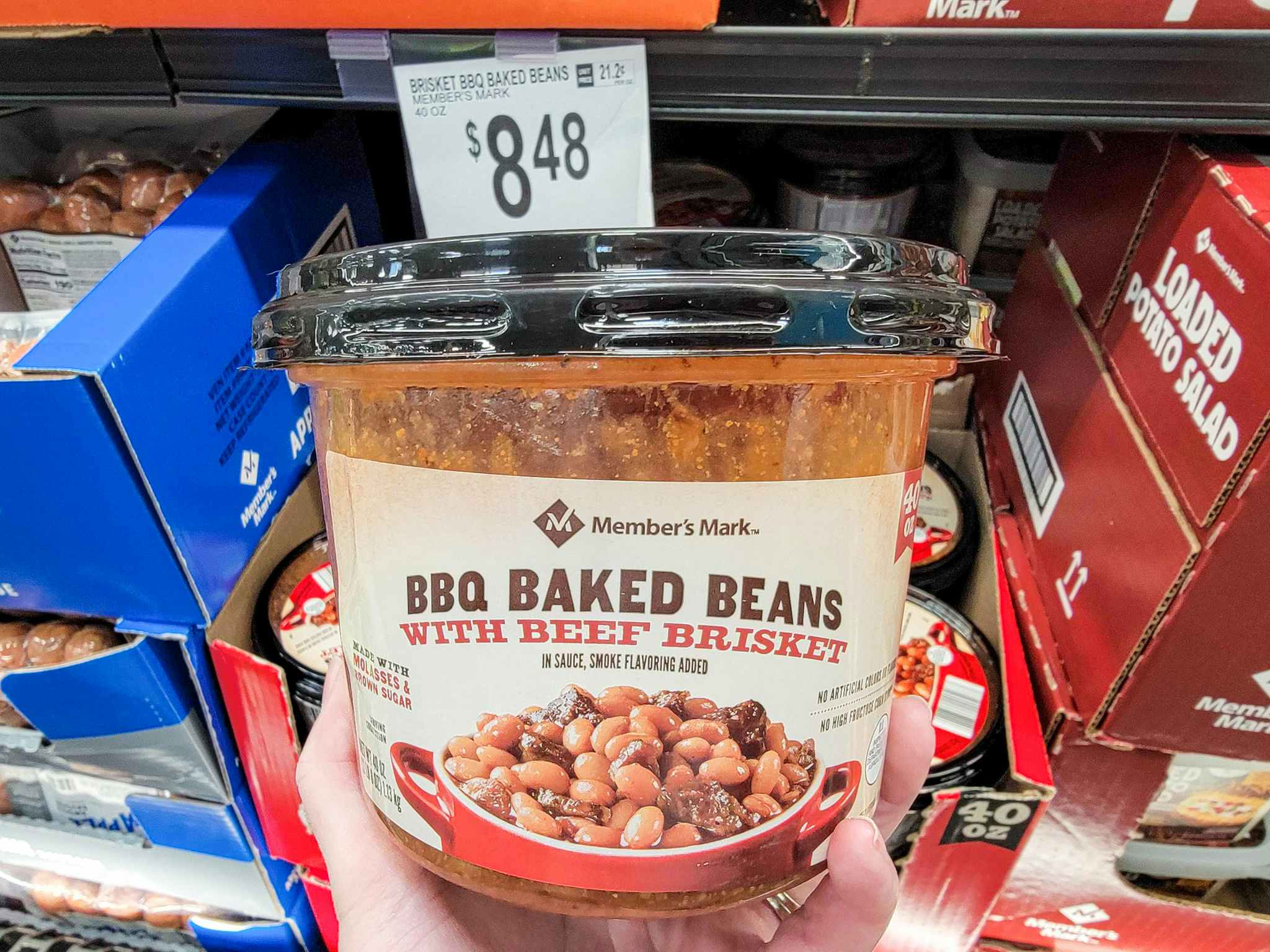hand holding a tub of bbq baked beans with brisket