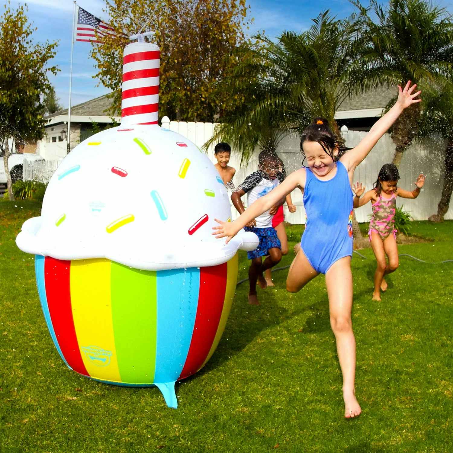 kids playing around a giant inflatable cupcake sprinkler