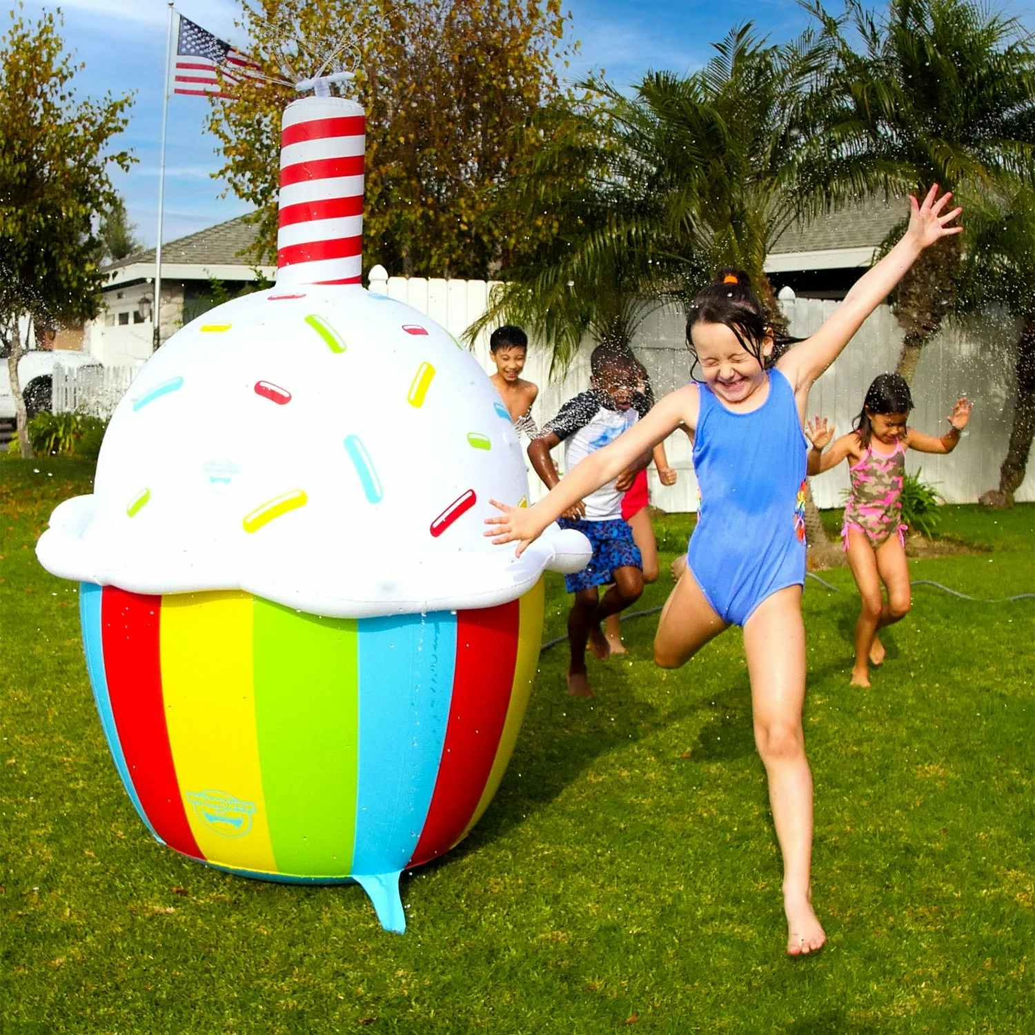 kids playing around a giant inflatable cupcake sprinkler
