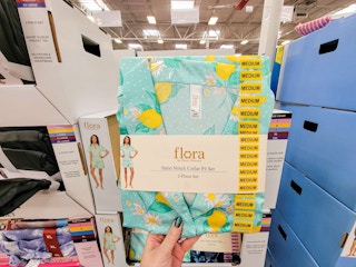 hand holding a set of teal satin pajamas with lemons on them