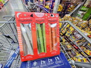 a box of halloween decorated pretzel rods in a cart, decorated as mummies, fingers, and monsters